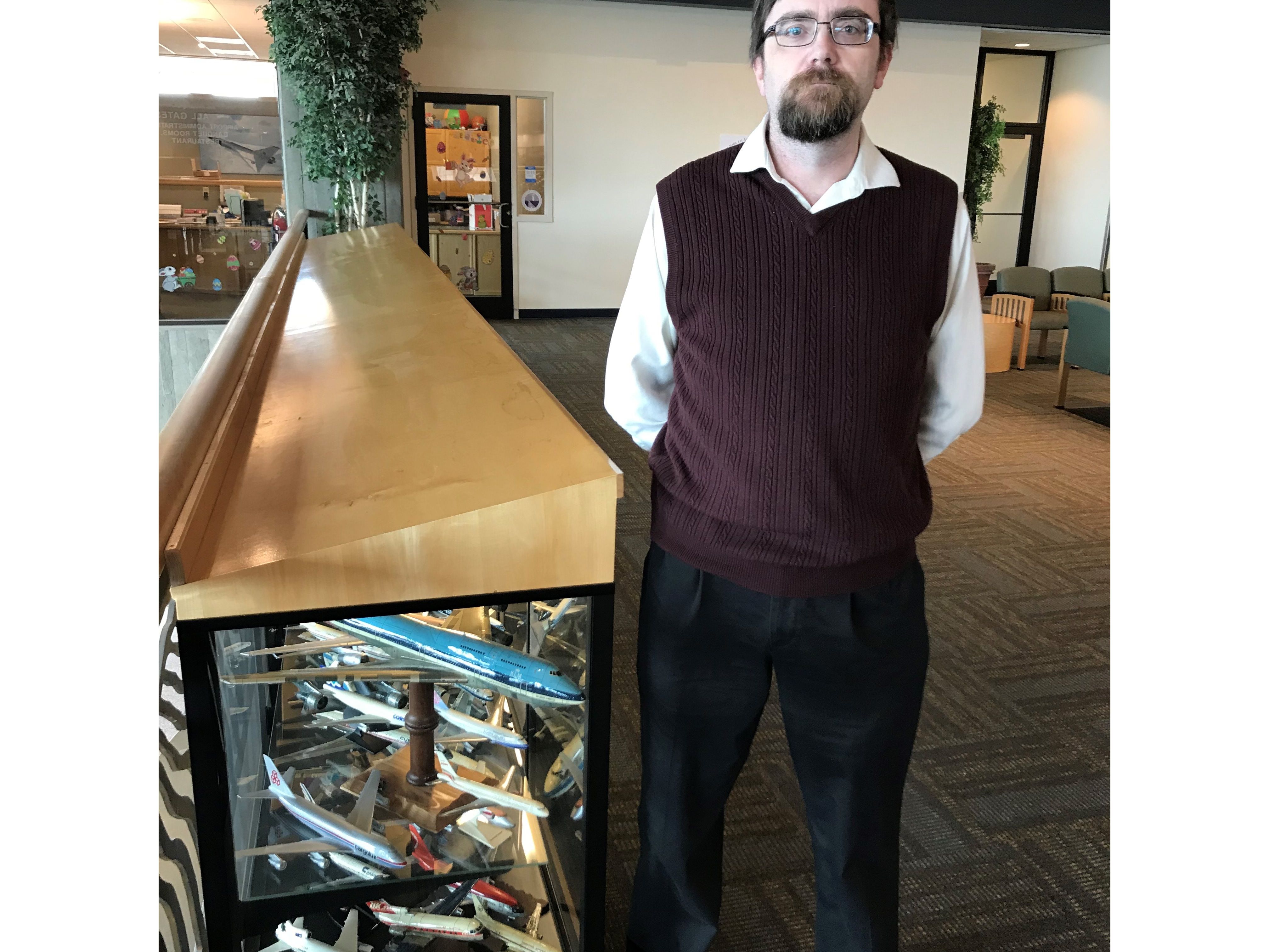 Benjamin Donnelly, an adjunct history professor at the University of Great Falls, poses next to one of two cases at the Great Falls International Airport that house the Poletto Collection, consisting of hundreds of model airliners crafted by his stepfather, Bary Poletto.